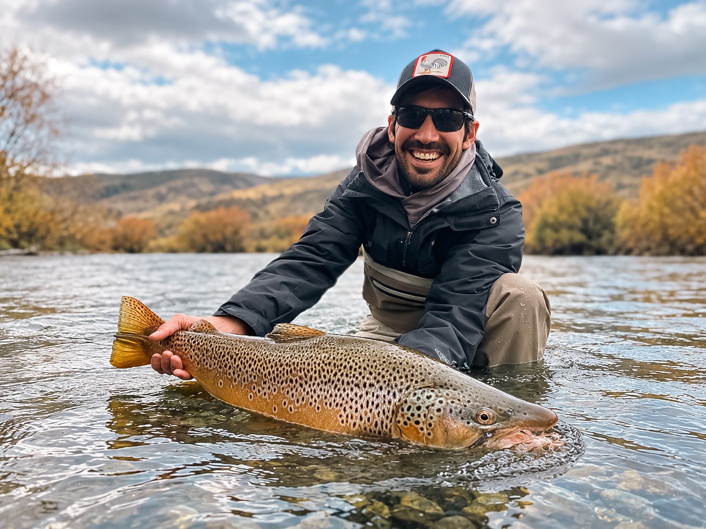 Fly fisherman holding a giant brown trout caught on the Limay River near Bariloche, Patagonia Argentina