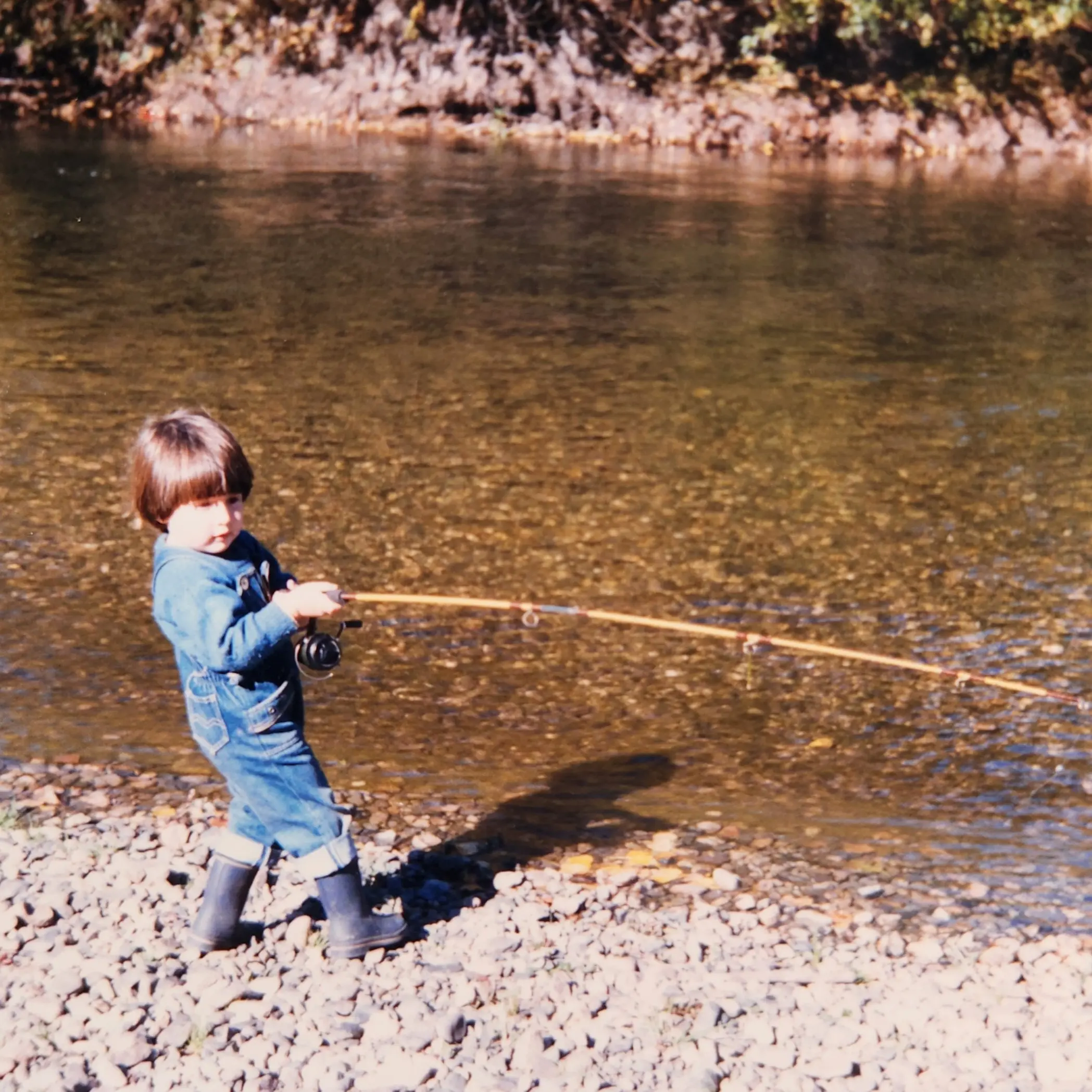 Three-year-old Emanuel Medina fishing with a rod on a Patagonian riverbank, the early days of the Trout Bariloche fishing family