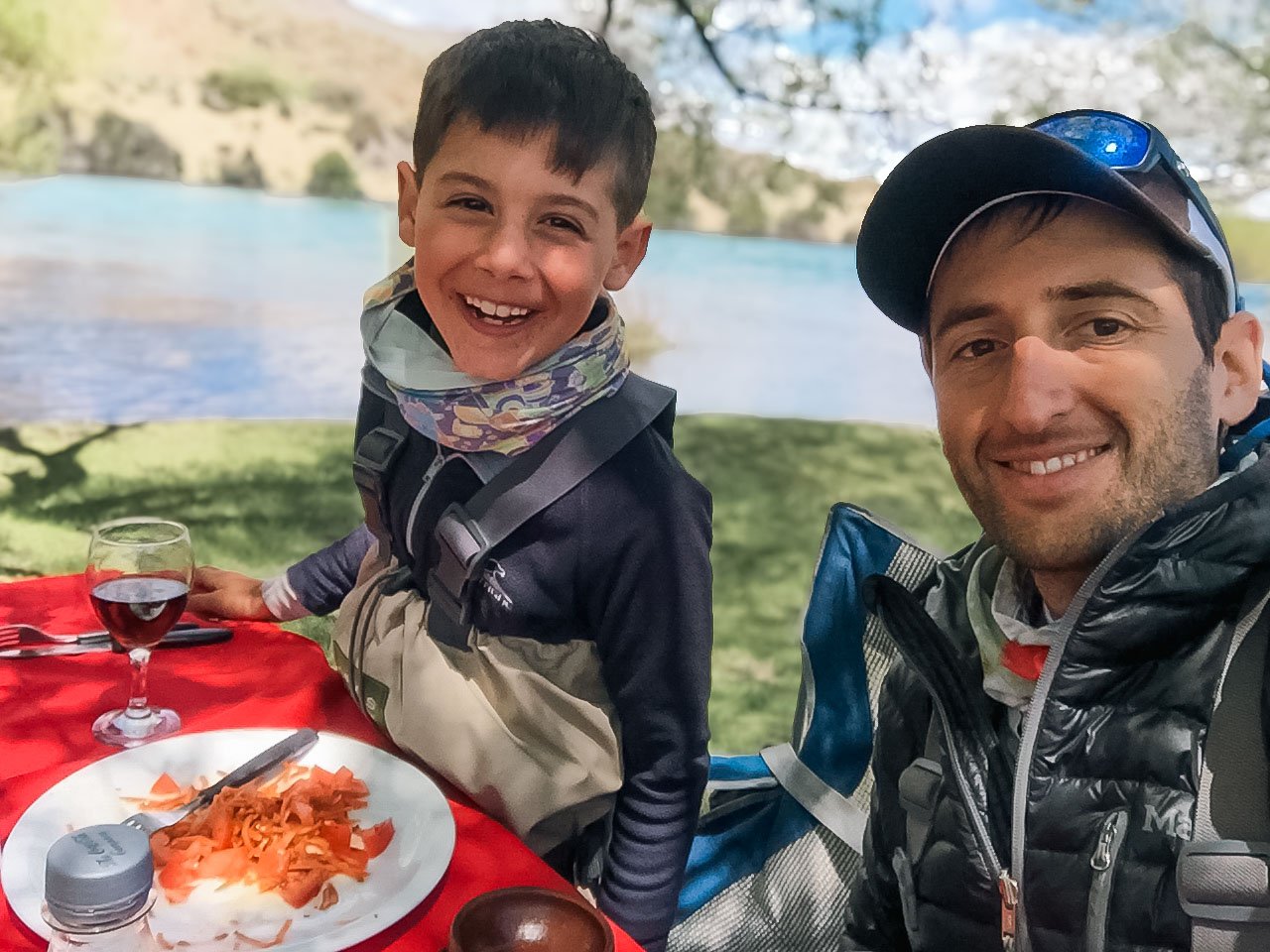 Emanuel Medina and a young angler smiling during a riverside lunch on a family fly fishing trip in Bariloche, Patagonia, Argentina