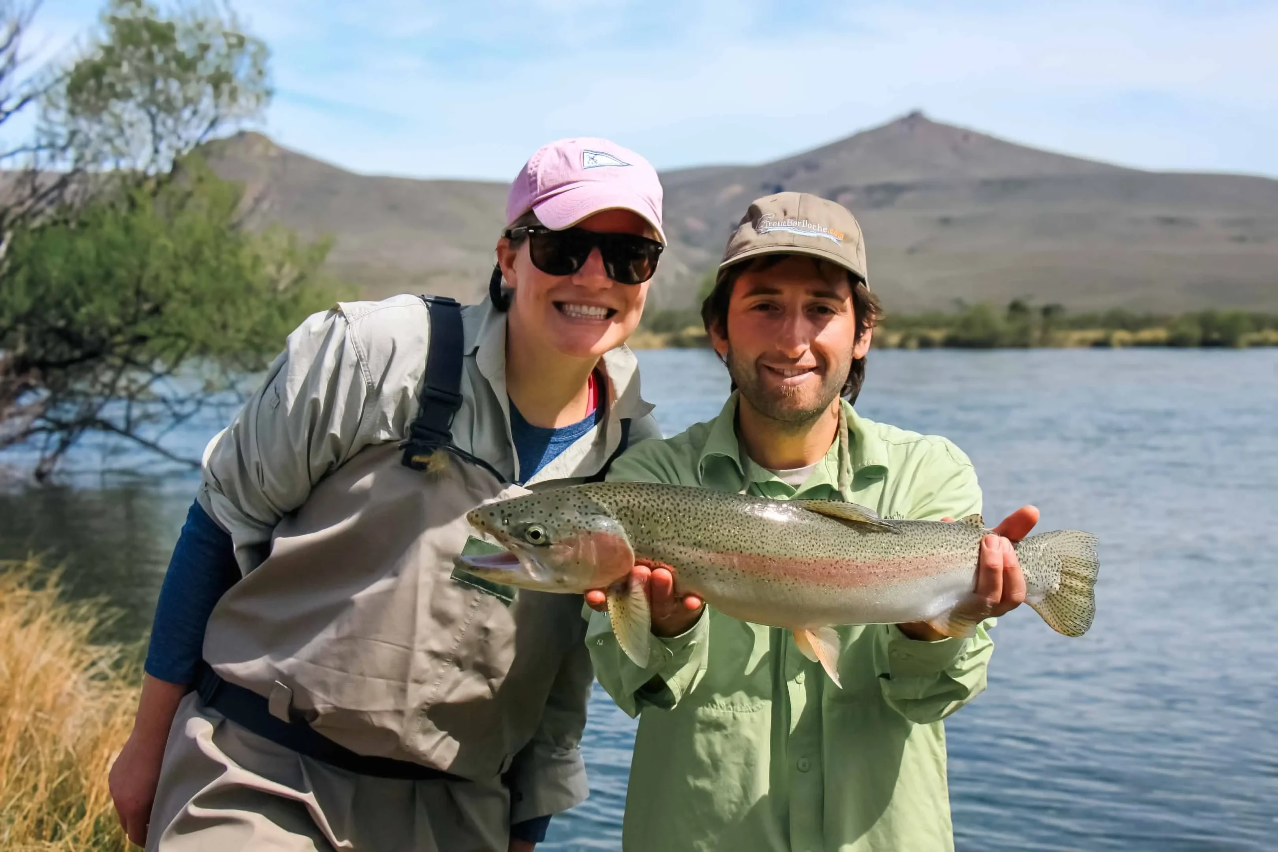 Young fly fishing guide Emanuel Medina and a smiling client holding a large trout together on a Bariloche fishing trip in Patagonia, Argentina