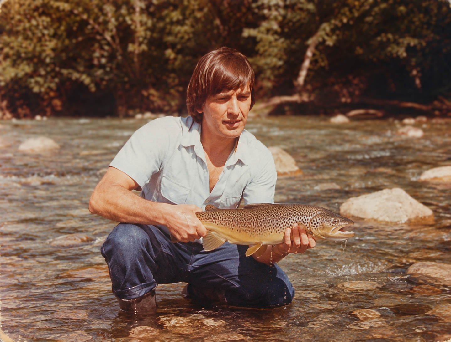 Hugo Medina, Emanuel's father, wading a Patagonian river and holding a brown trout he caught fly fishing in Bariloche, Argentina